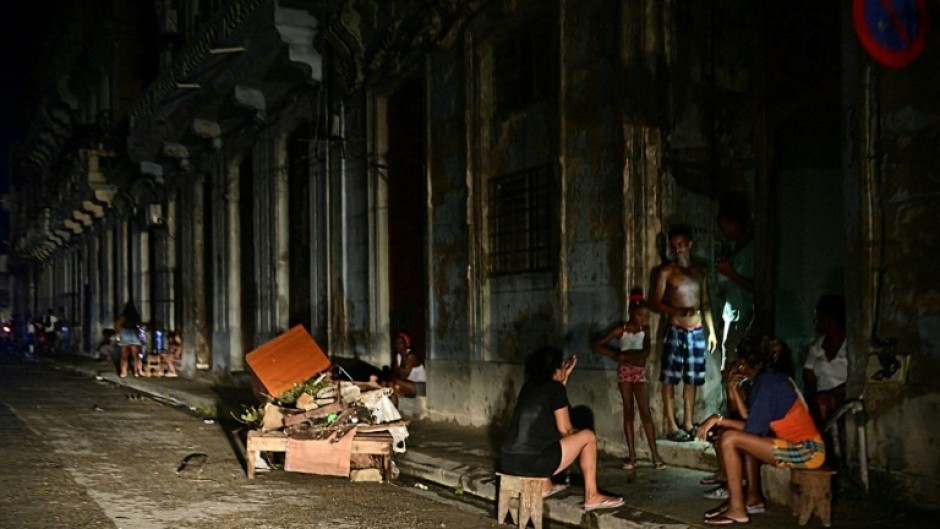 Cubans chat at night on a street during a nationwide blackout in Havana