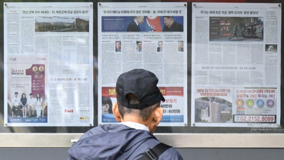 A man walks past a newspaper displayed on a street in Seoul with coverage on North Korea's decision to deploy thousands of soldiers to Russia