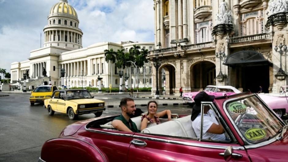 Tourists ride in a classic American car through the streets of Havana 