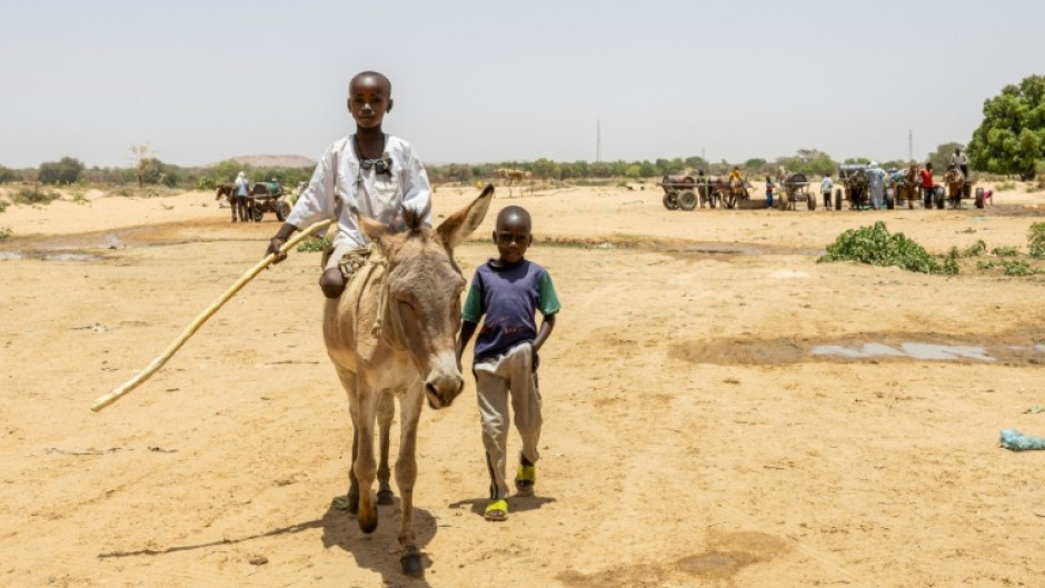 Two young boys cross the border between Chad and Sudan at the Koufroun refugee camp