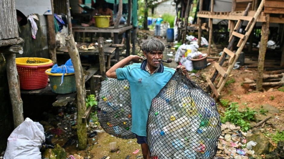 A Moken fisherman carries bags of plastic waste to sell to Tide staff members at his fishing village on Thailand's southern island of Koh Chang