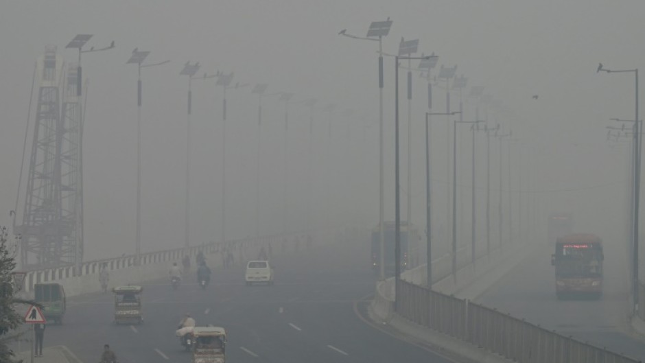 Commuters drive along a road amid heavy smog in Lahore