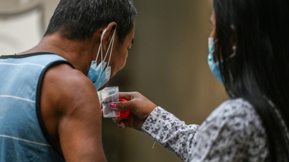 A man spits a sputum sample during a tuberculosis screening at a health centre in Valenzuela in the Philippines