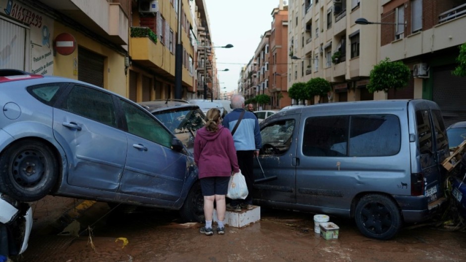 Residents stand in front of piled up cars following deadly floods in Alfafar neighbourhood, south of Valencia