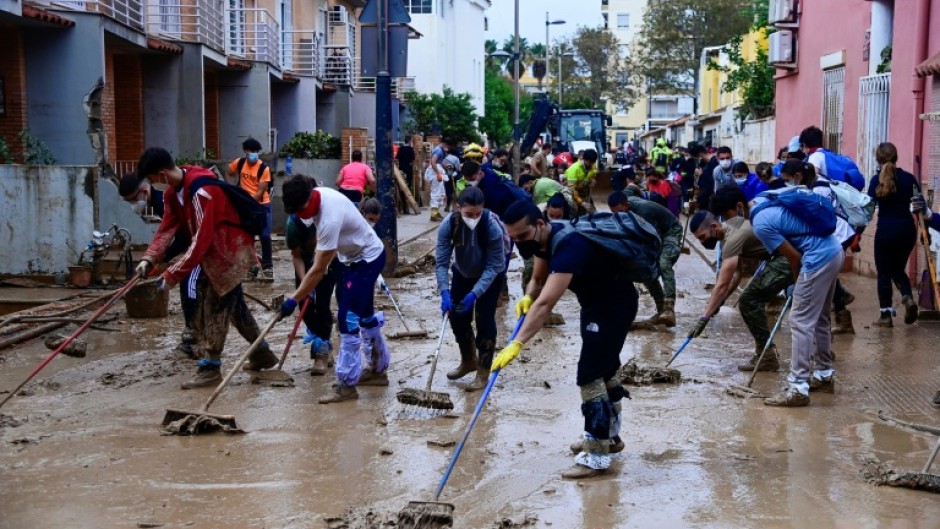 People clear mud from a street in Alfafar in the region of Valencia, eastern Spain