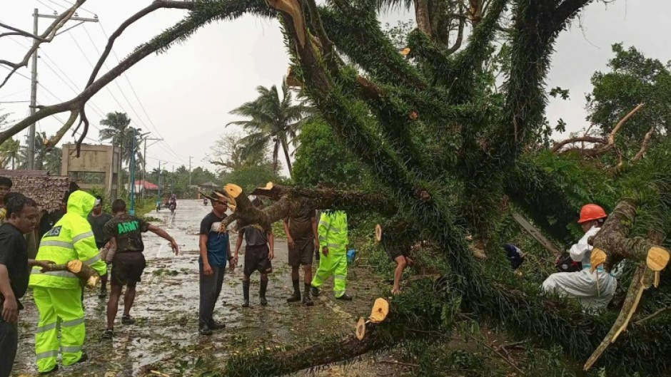 Government workers remove a fallen tree on a highway in Casiguran, Aurora province, after Typhoon Toraji hit the nation's northeast coast