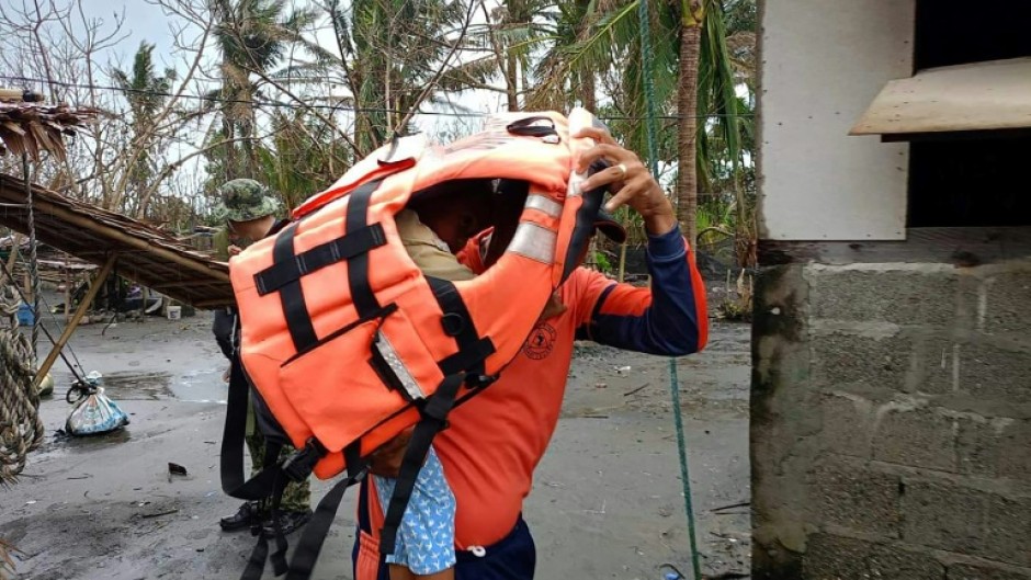 A rescuer carries a young resident during a forced evacuation operation in the northern Philippines ahead of Typhoon Usagi's landfall