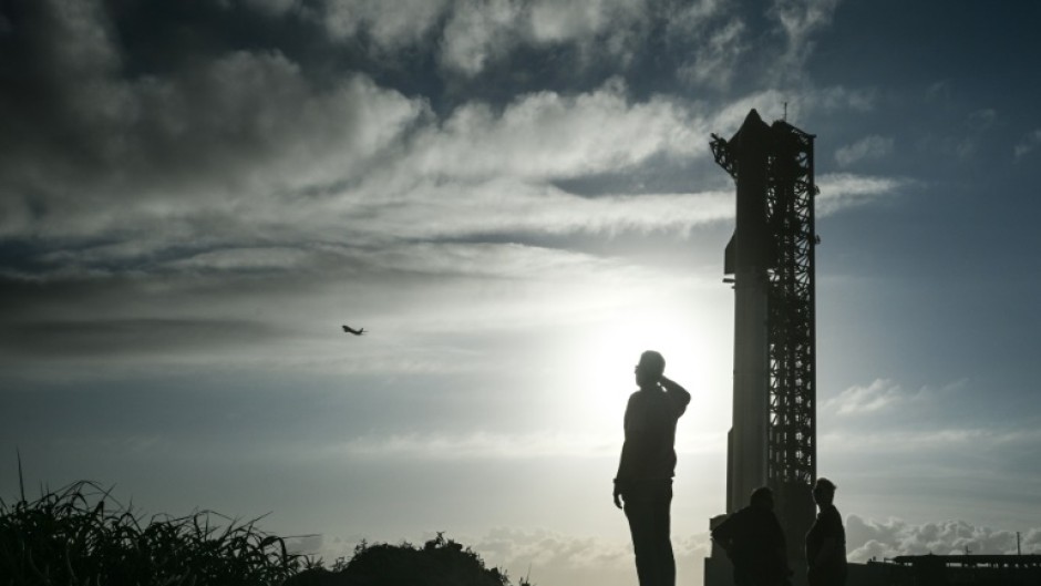 A man watches a SpaceX plane as it flies past the SpaceX Starship at the launch pad ahead of its sixth flight test from Starbase in Boca Chica, Texas