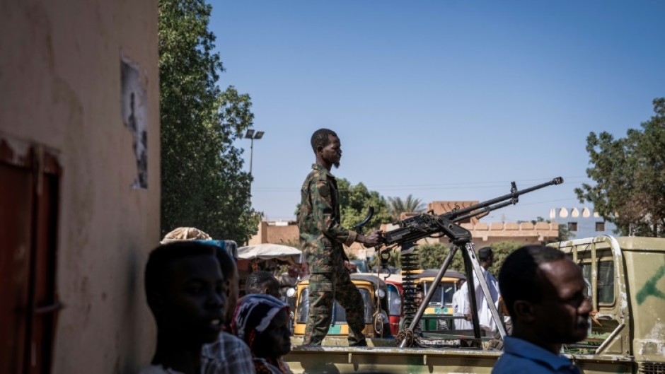 A Sudanese army soldier mans a machine gun on top of a military pickup truck outside a hospital in Omdurman