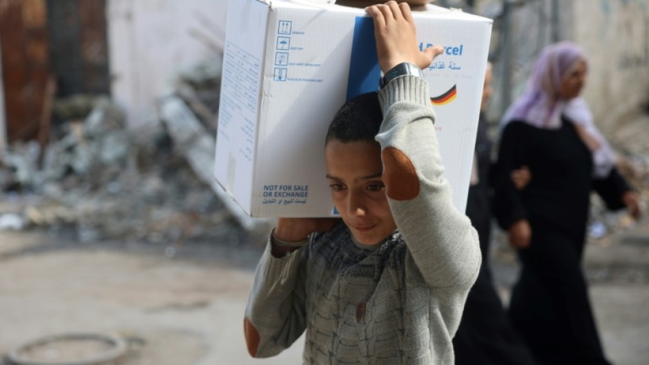 A boy carried a box of humanitarian aid back to his home in central Gaza's Al-Bureij refugee camp