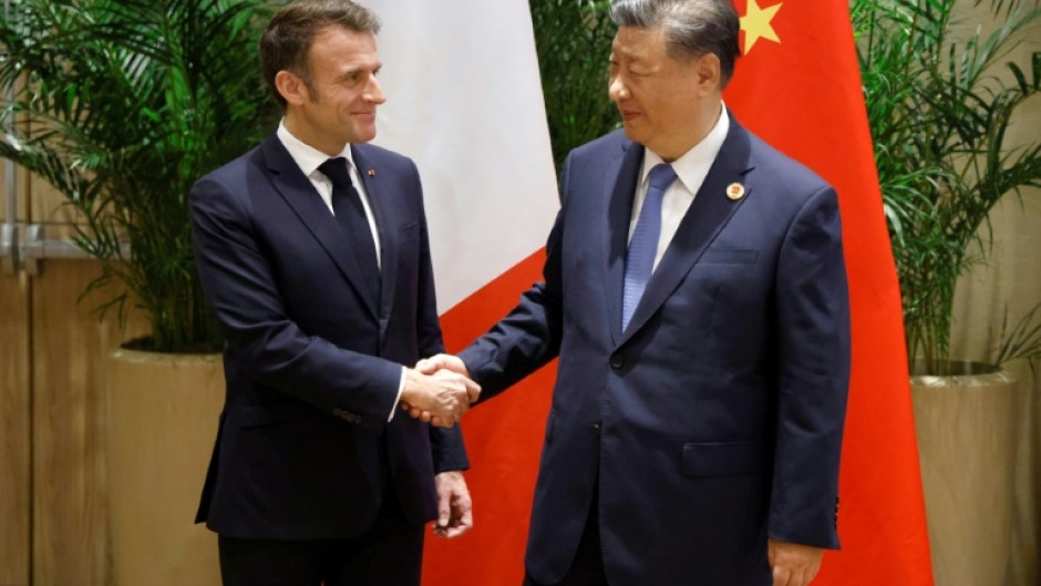 French President Emmanuel Macron (L) shakes hands with China's President Xi Jinping during a bilateral meeting on the sidelines of the G20 summit in Rio de Janeiro, Brazil