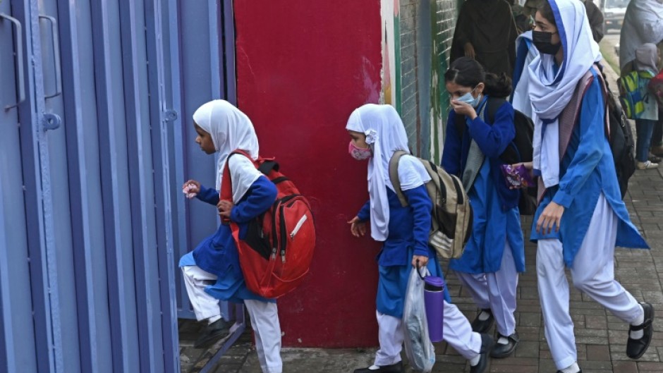 Students wearing masks arrive for classes as schools reopened amid smoggy conditions in Lahore on Wednesday