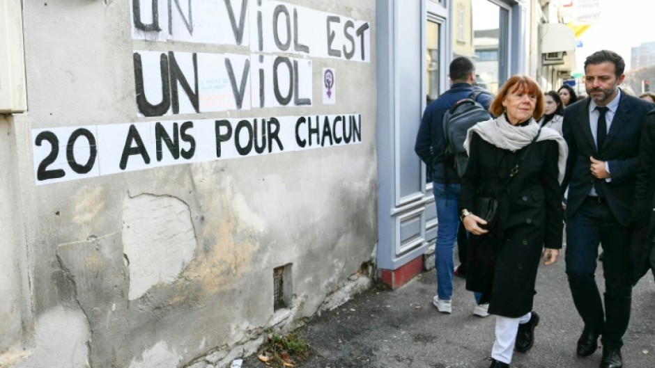 Gisele Pelicot (2nd R) walks past posters reading "Rape is rape. 20 years for every one of them" outside the Avignon courthouse