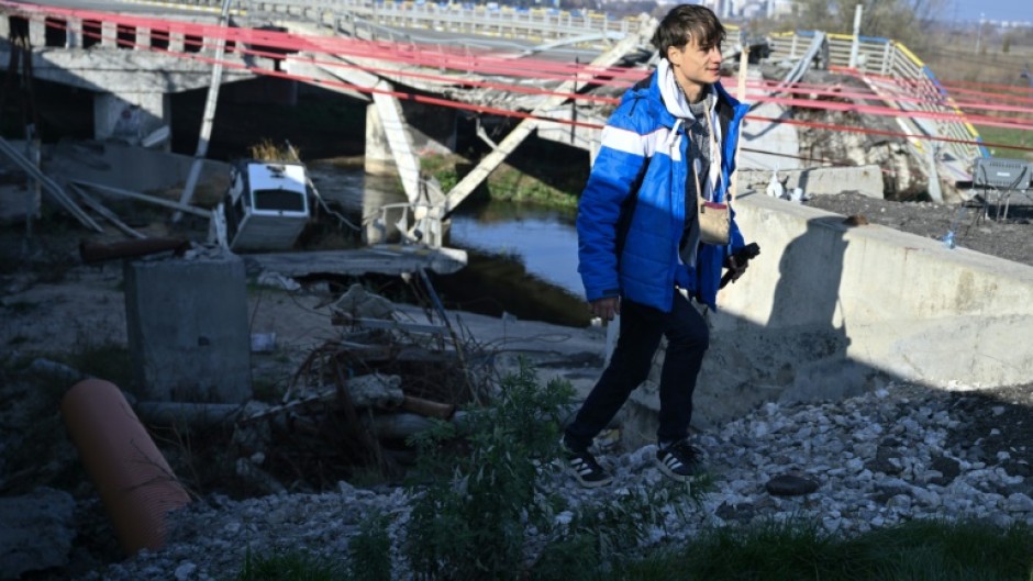 Spanish traveller Alberto Blasco Ventas walks next to the destroyed Irpin bridge in Ukraine which has become a hotspot for thrill-seeking tourists