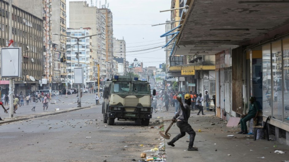 A protester throws a stone at an armoured vehicle during clashes in Mozambique's capital Maputo 