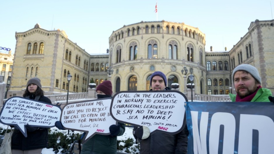 Protesters hold placards during a demonstration against seabed mining outside the Norwegian Parliament building in Oslo