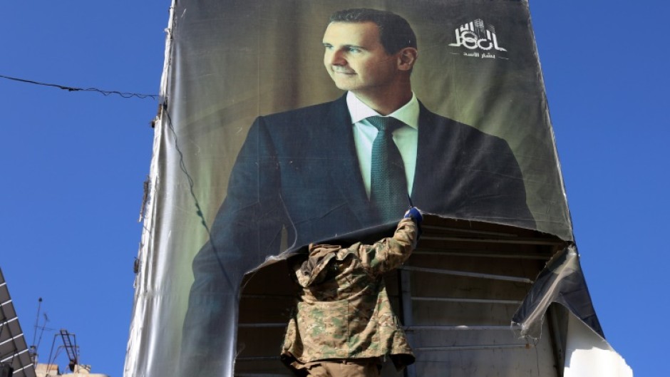 A rebel tears down a picture of Assad in Aleppo