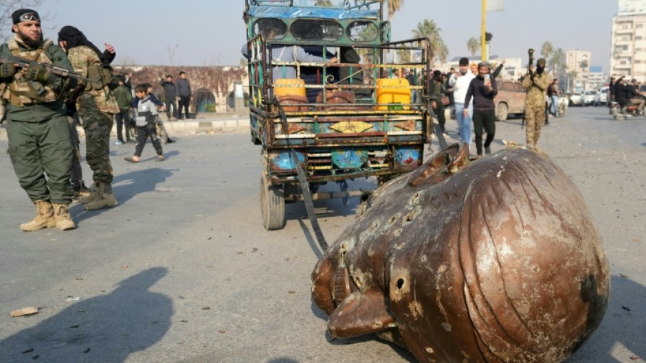 A truck pulls the head from the toppled statue of late Syrian president Hafez al-Assad through the streets of the captured Syrian city of Hama