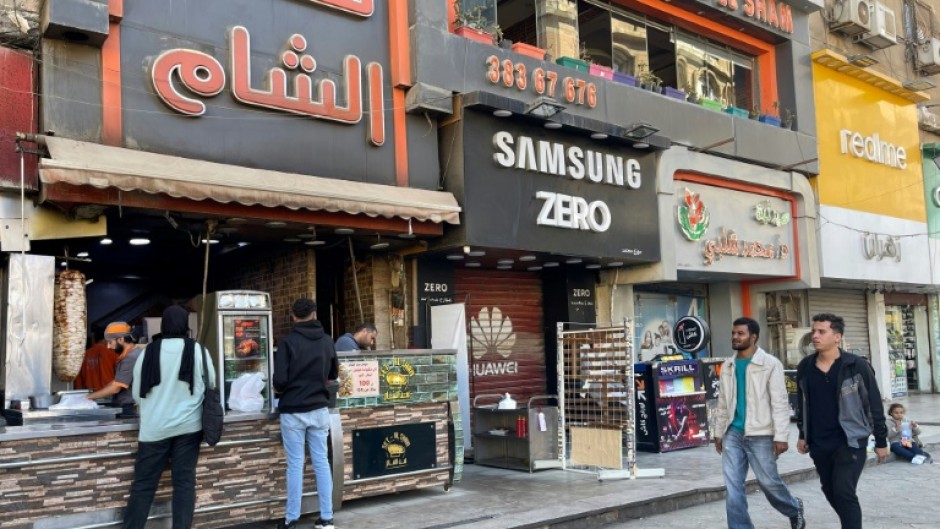 People pass a Syrian restaurant in western Cairo, where Syrian businesses have clustered, and the air buzzed with celebration after the fall of Bashar al-Assad in Damascus