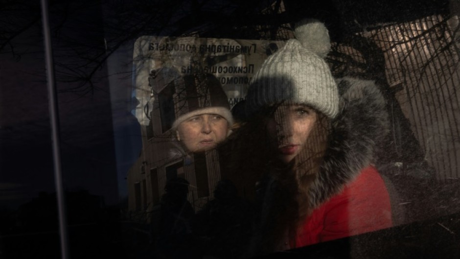 Anna (R), 21, and her mother (L) sit in a minivan as they wait at an evacuation point outside the city, in the eastern Donetsk region, on December 14, 2024, as Russian troops advanced close to the city.