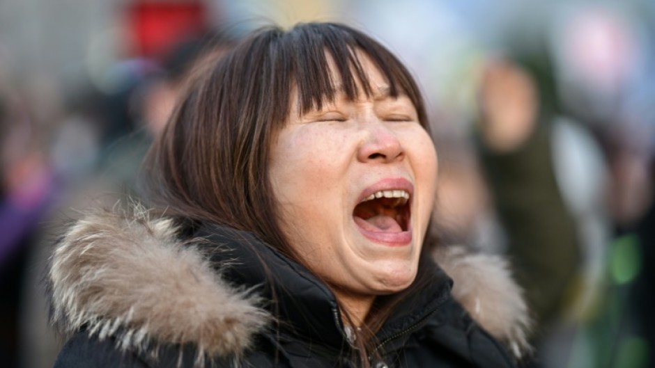 A protester calling for the ouster of South Korea President Yoon Suk Yeol reacts after the result of the second martial law impeachment vote outside the National Assembly in Seoul on December 14, 2024. South Korean lawmakers on December 14 voted to remove President Yoon Suk Yeol from office for his failed attempt to impose martial law last week.