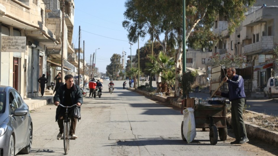 A Syrian man rides his bicycle down a street in the town of in Qusayr in Syria's central Homs province