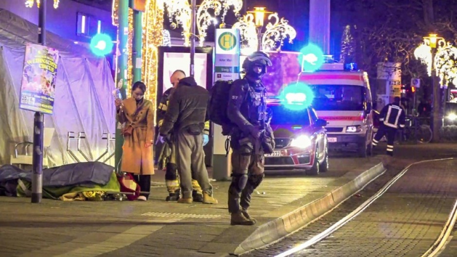 An injured person is lying on a stretcher as police and ambulances stand next to the Christmas market attack scene