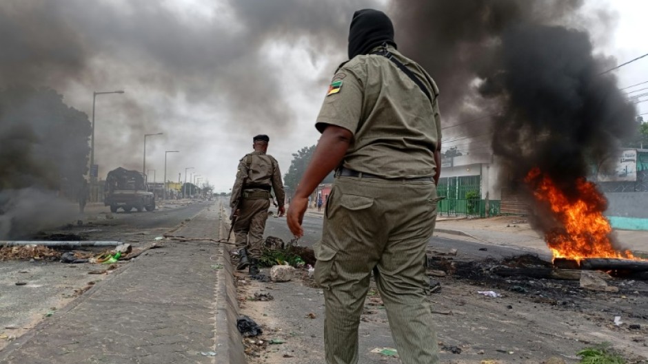 Mozambican security forces next to a burning barricade in Maputo on Tuesday