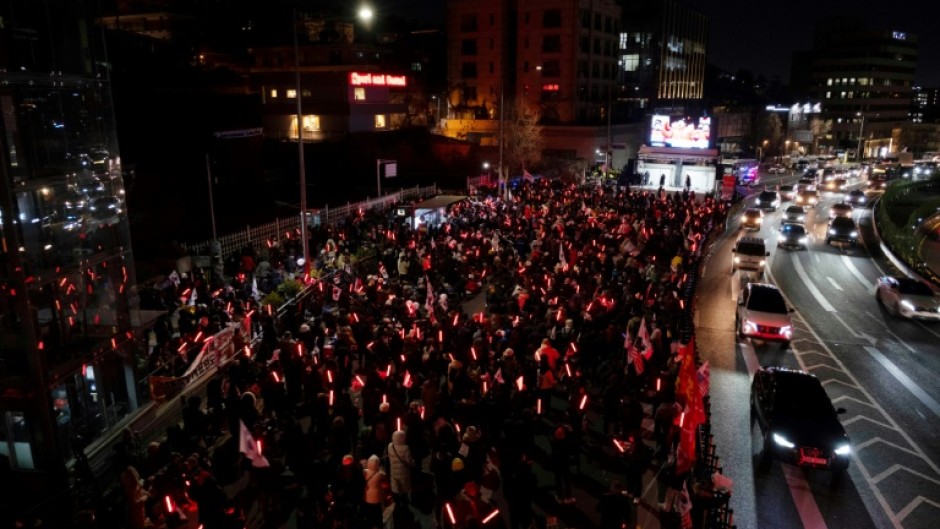 Supporters of deposed South Korean president Yoon Suk Yeol demonstrate near his residence brandishing glowsticks