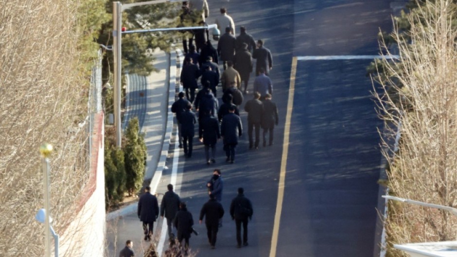 Anti-corruption investigators walk up a hill inside the presidential residence of impeached South Korea President Yoon Suk Yeol in Seoul on Friday