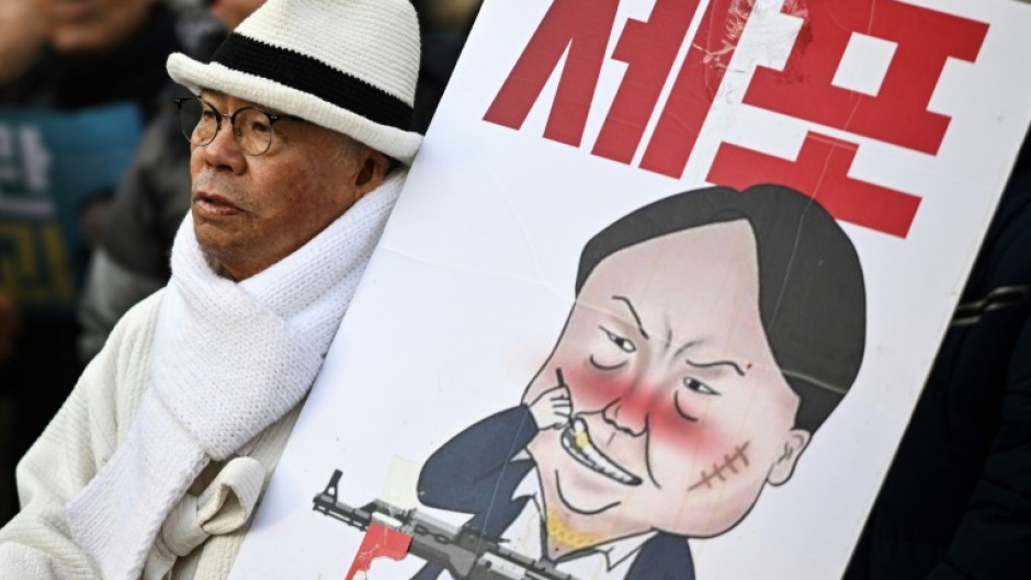 A man carrying a placard with a comic depicting South Korea's impeached president Yoon Suk Yeol