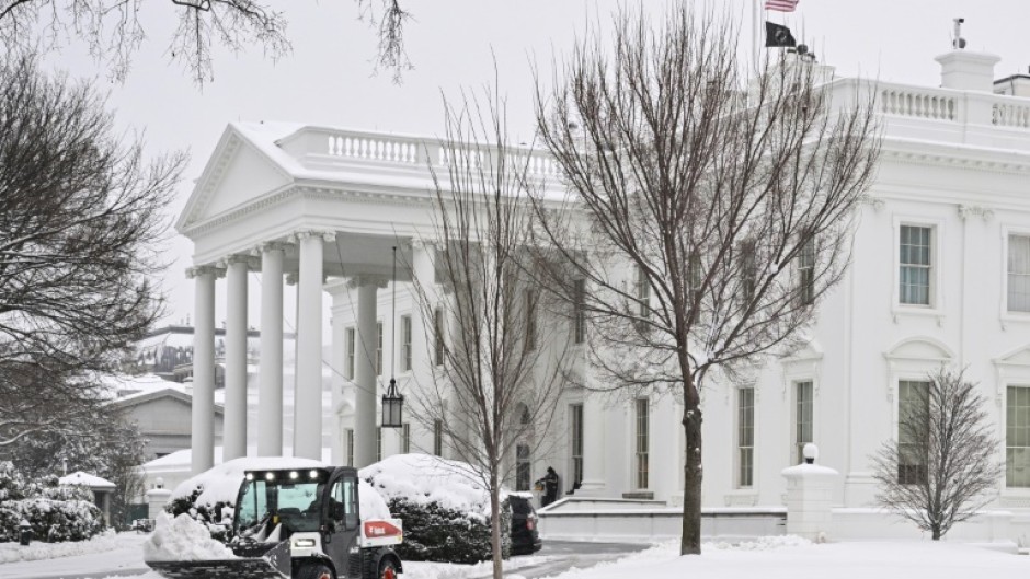 Workers remove snow outside the White House in Washington