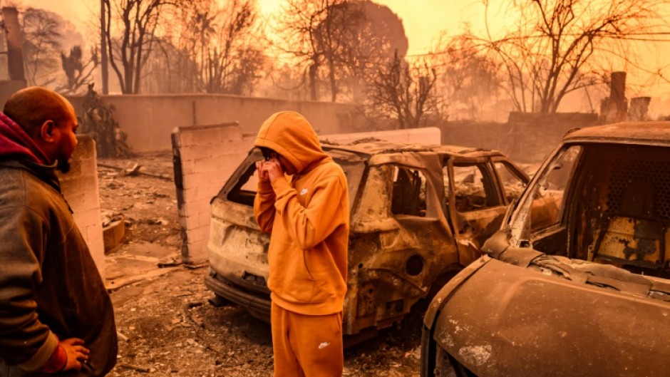 Lebron Jones wipes his eyes while viewing his burned home