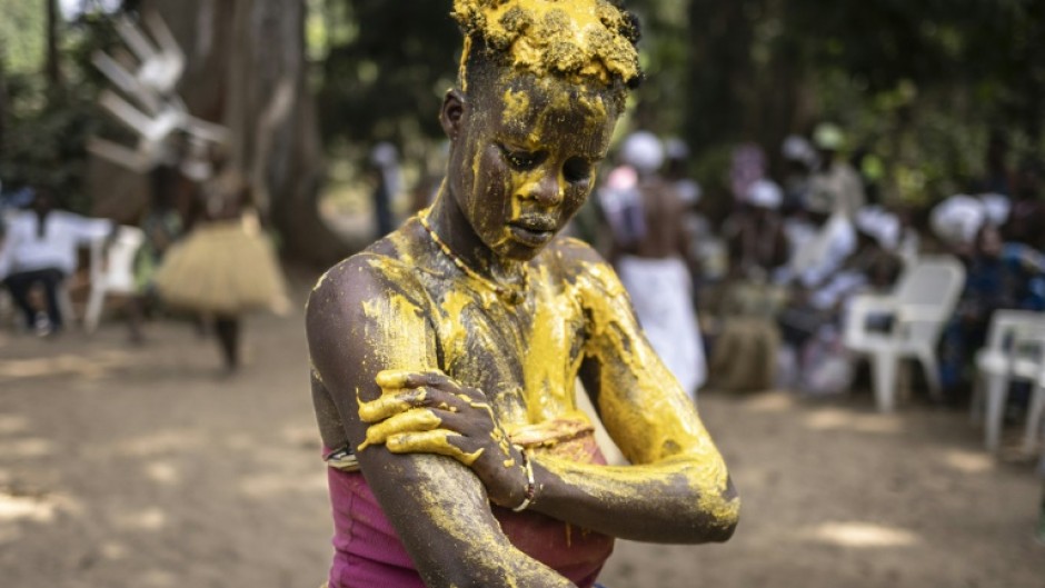 An initiate Kokou, a traditional warrior deity, covers herself with a mixture of red vegetable oil mixed with corn flour as festivities get under way 