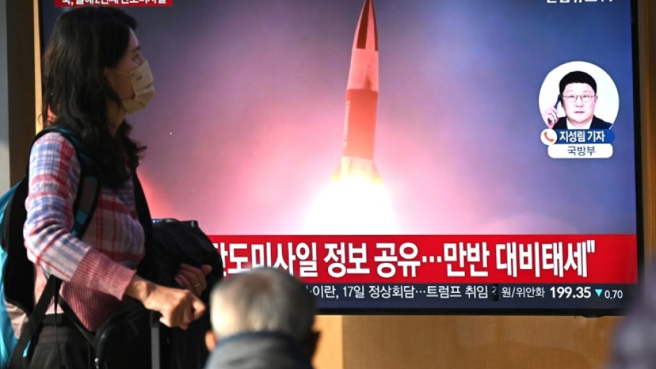 People watch a television screen showing a news broadcast with file footage of a North Korean missile test, at a train station in Seoul