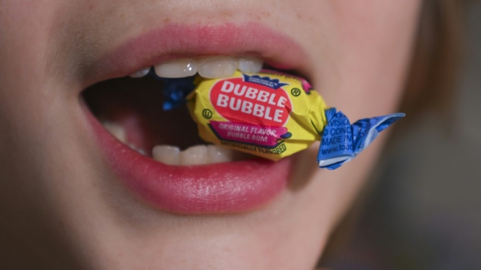 A boy holds a wrapped Dubble Bubble Bubble Gum candy in his mouth, a product that uses Red Dye No 3, in this illustration photograph on December 27, 2024