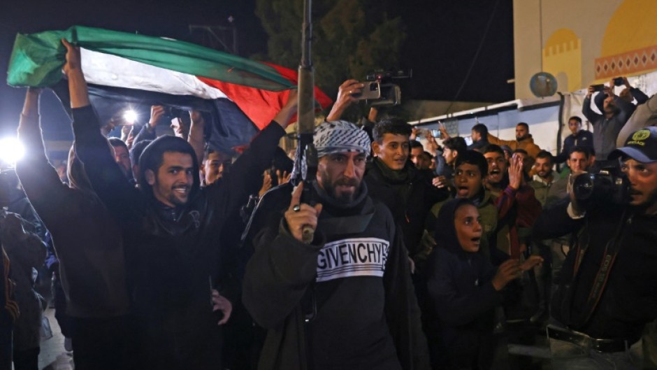 People celebrate while watching a television along a street in Khan Yunis in southern Gaza on January 15, 2025 as news spread that a ceasefire had been reached