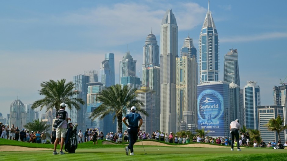 Northern Ireland's Rory McIlroy (R) putts on the eighth hole during the first day of the Dubai Desert Classic