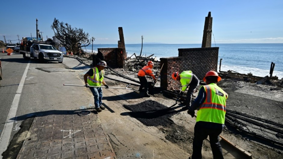 Workers on January 17, 2025 repair a road damaged by a fire that tore through the Los Angeles area 