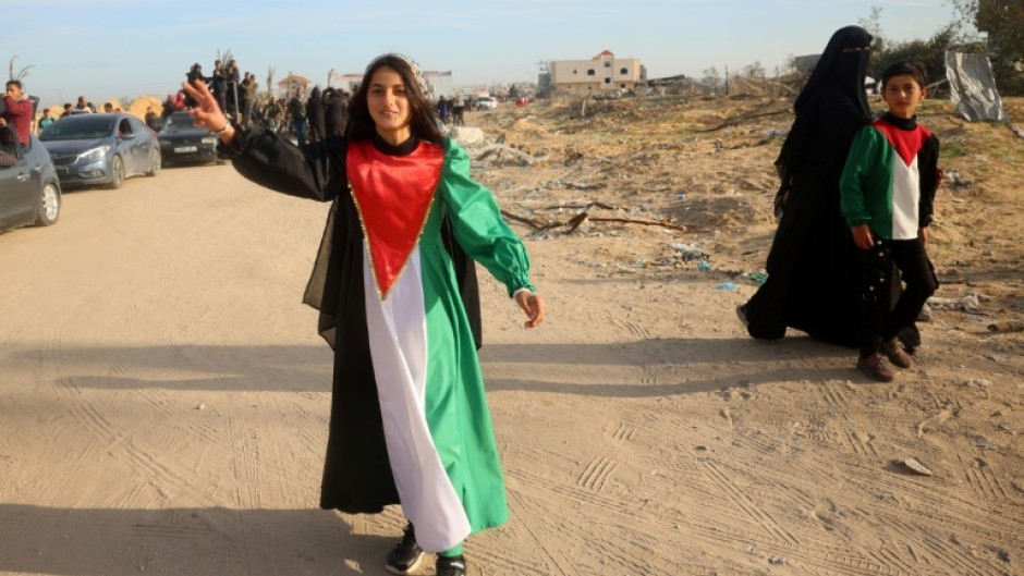 A young woman wears a dress in the colours of the Palestinian flag, celebrating the ceasefire