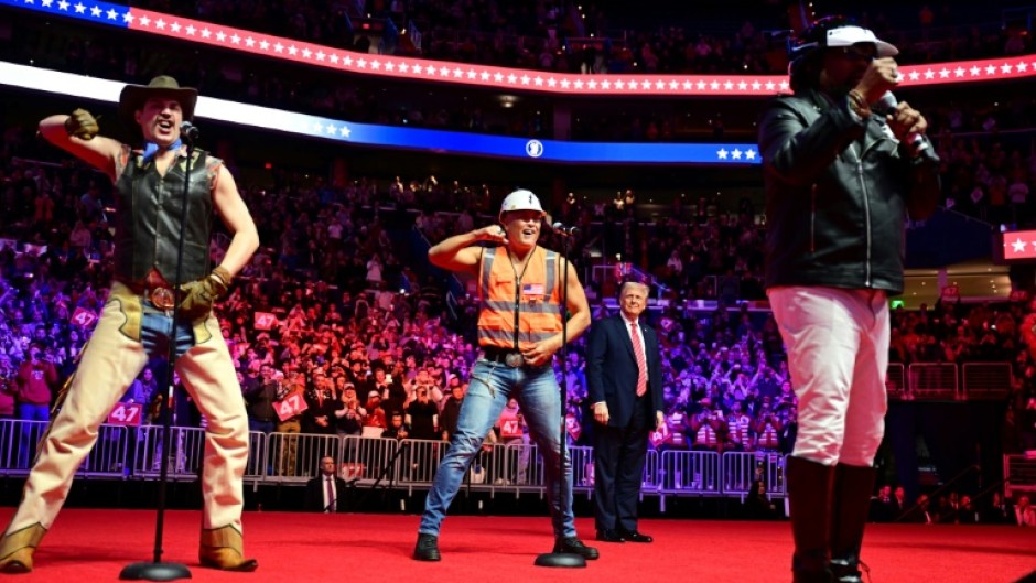 Trump looks on as the Village People perform at the MAGA victory rally at the Capital One Arena in Washington