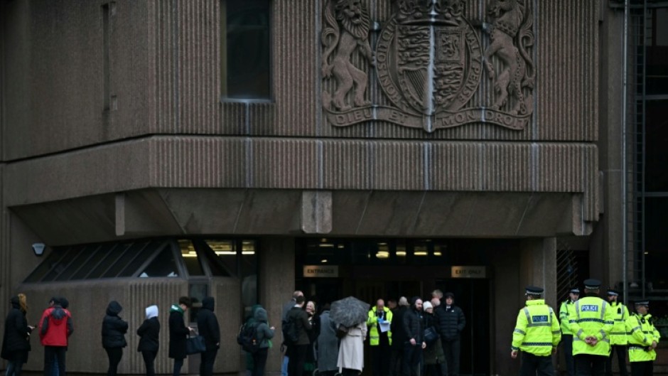 Police officers stand on duty outside The Queen Elizabeth II Law Courts in Liverpool as people arrive for the opening of the trial of a teenager charged with killing three young girls in a stabbing spree in August 2024 