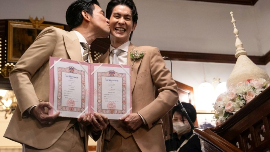 Thai actors Apiwat 'Porsch' Apiwatsayree (L) and Sappanyoo 'Arm' Panatkool pose after registering their same-sex marriage Thursday