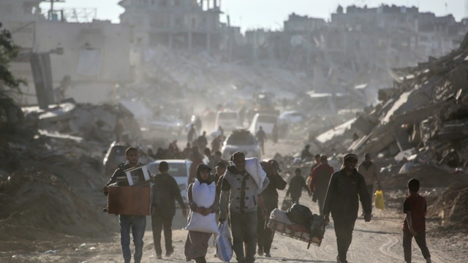 Palestinians carry their belongings as they return to Rafah in southern Gaza, surrounded by destruction