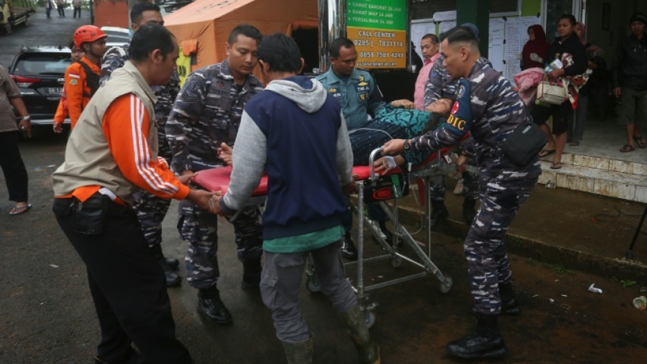 A survivor is brought to an Indonesian hospital from the site of a landslide triggered by heavy rain