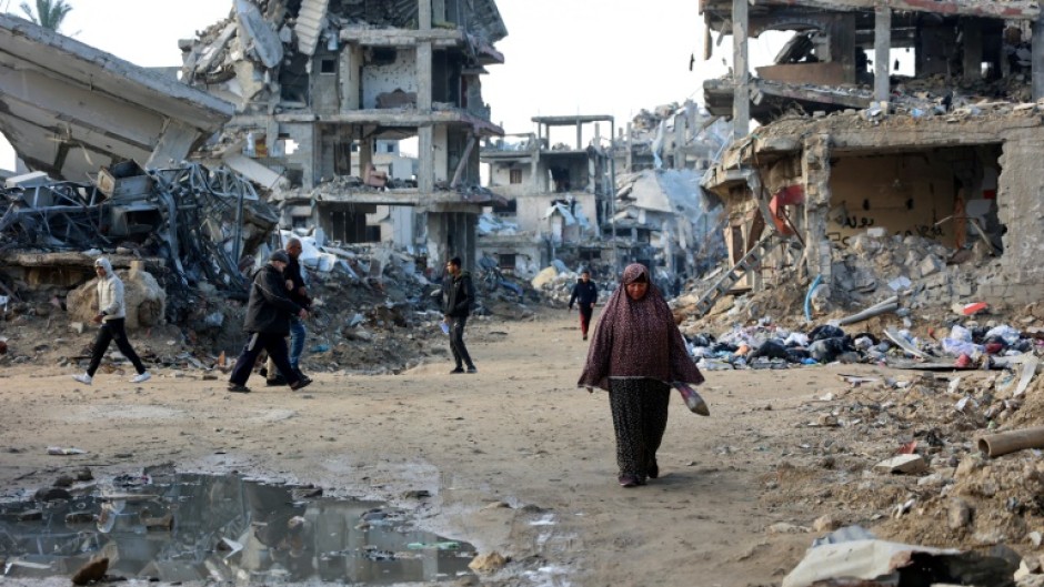 Palestinians walk amid the destruction in the Shujaiya neighbourhood of Gaza City