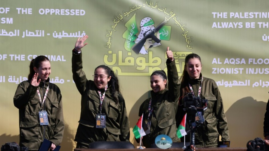 Four Israeli hostages wave on a stage before Hamas fighters hand them over to a team from the Red Cross in Gaza City