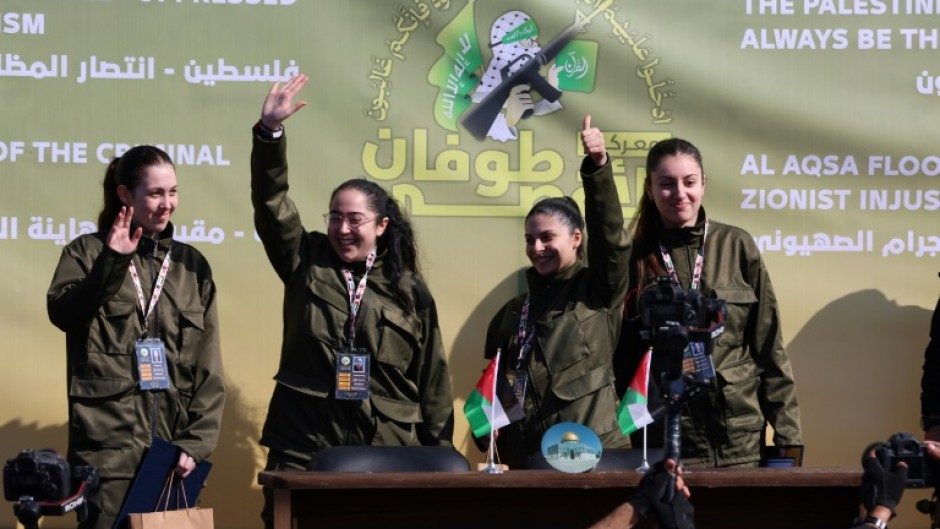 Four Israeli hostages wave on a stage before Hamas fighters hand them over to a team from the Red Cross in Gaza City