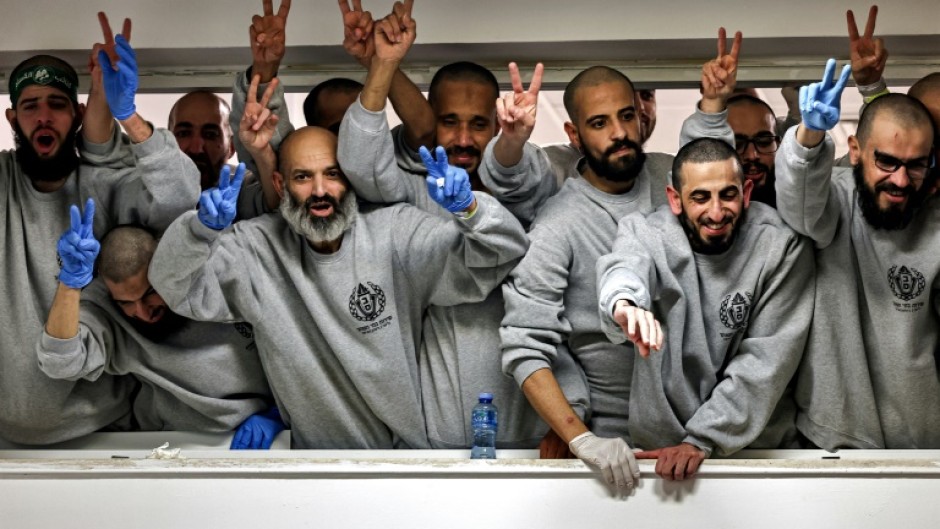 Freed Palestinians still wearing their grey prison tracksuits wave to well-wishers as they arrive in the West Bank city of Ramallah for a health check.