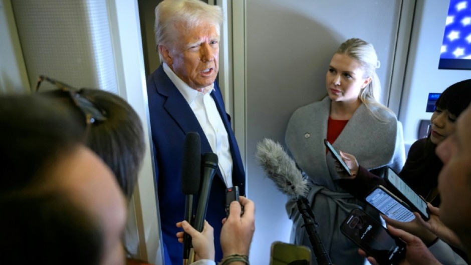 US President Donald Trump speaks with the press, alongside White House Press Secretary Karoline Leavitt (R), on board Air Force One 